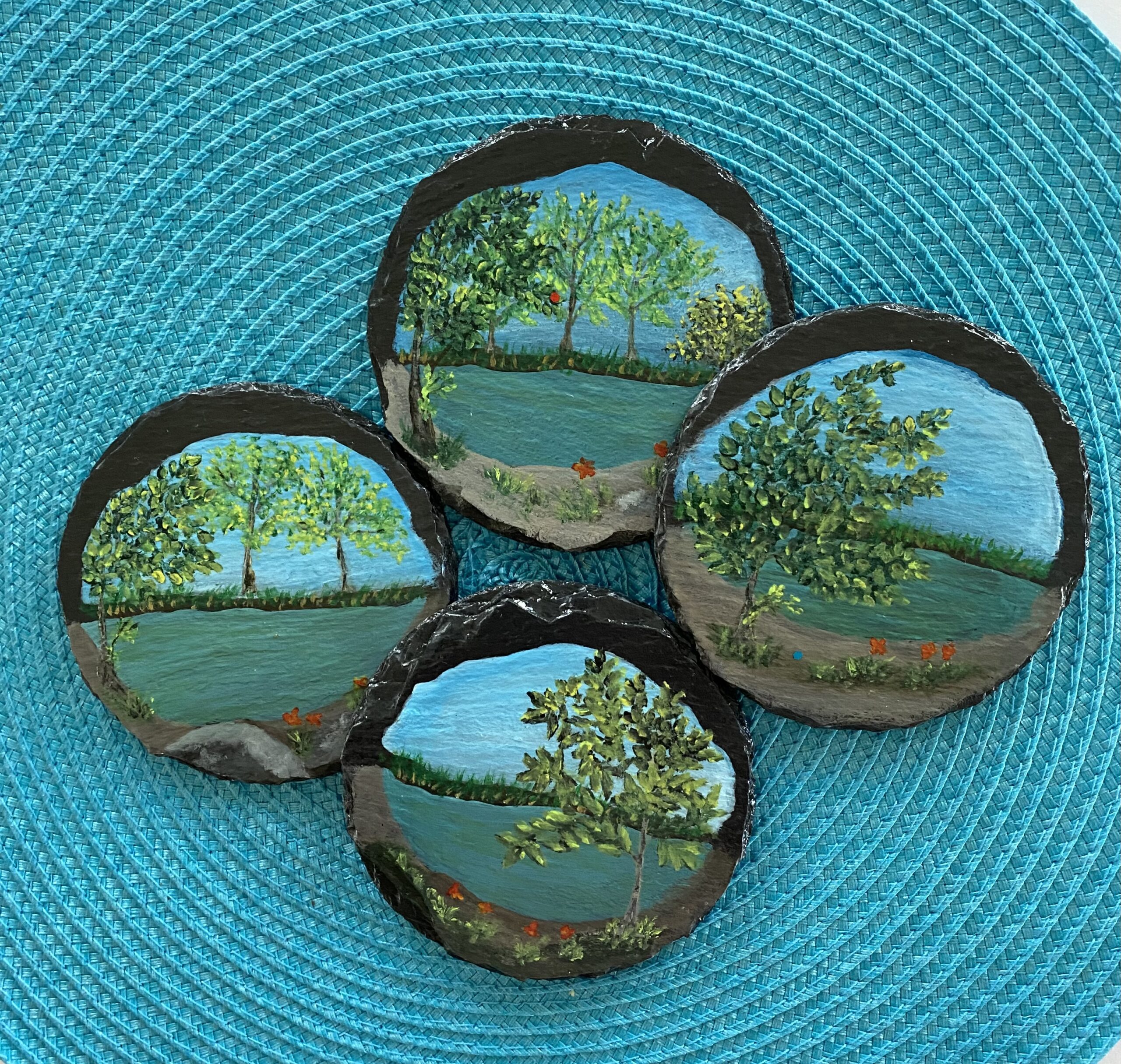 Set of 4 coasters painted with images of a pond and trees