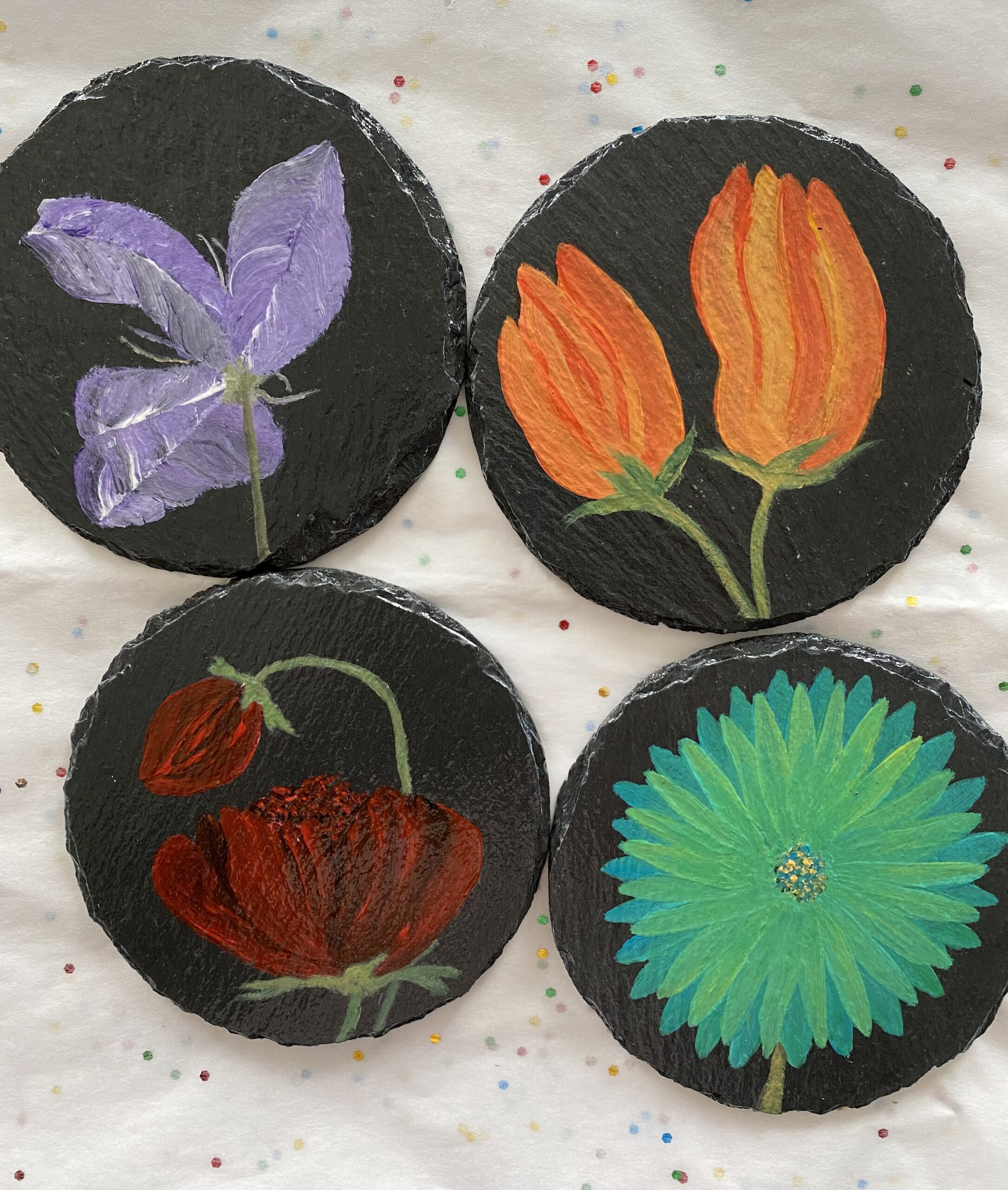 Set of 4 coasters, each with an image of a different flower painted on it