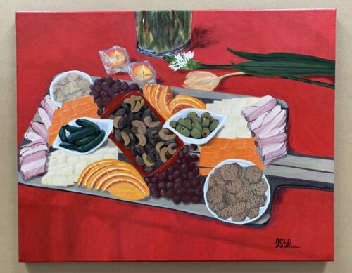 Large charcuterie board with foods on a red table cloth