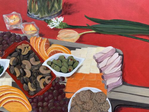 Large charcuterie board with foods on a red table cloth