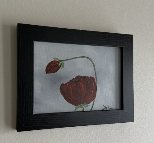 A painting of red poppies on a grey background in a black frame