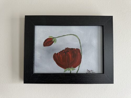 A painting of red poppies on a grey background in a black frame