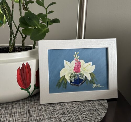 A painting of white lilies in a blue glass vase in a white frame