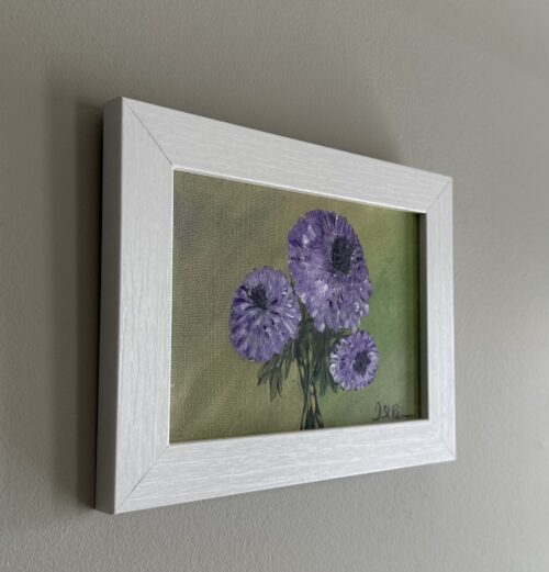 A painting of purple Chrysanthemums on a green background and in a white frame