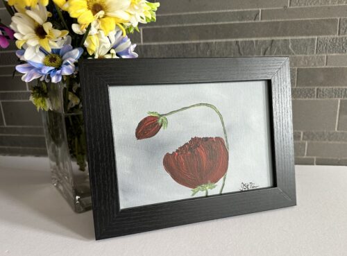 A painting of red poppies on a grey background in a black frame