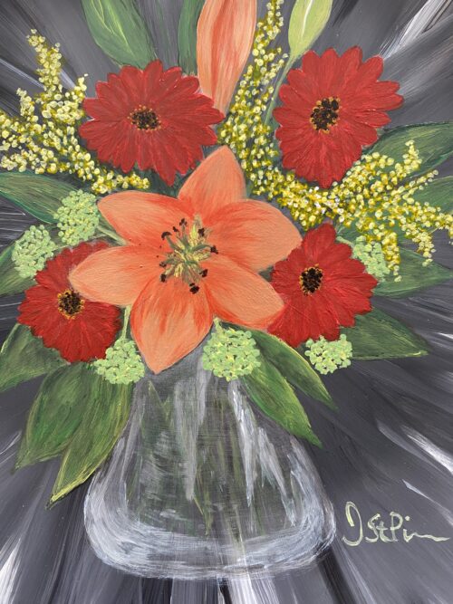 Photo of a black hand painted plate with mixed orange and red flowers in a clear glass vase