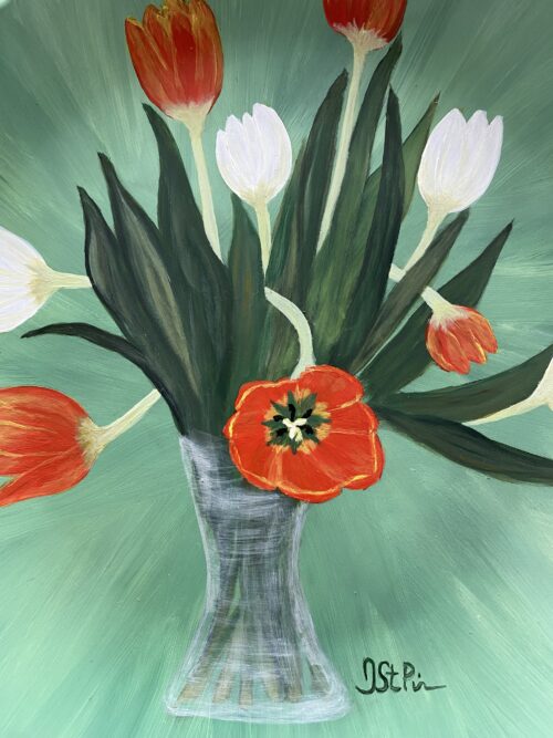 Photo of a green plate hand painted with orange and white twisting tulips in a glass vase